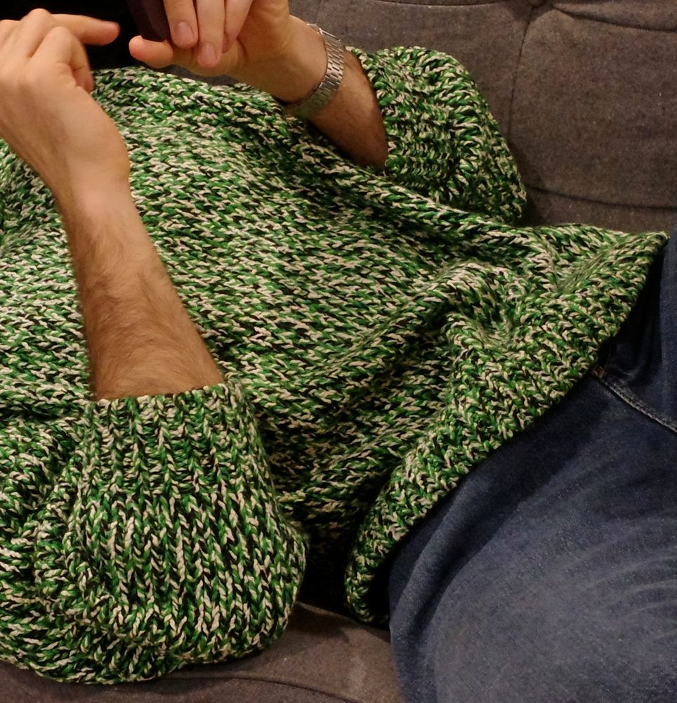 Picture of a person wearing a knit sweater that is colored green, white & black in a pattern reminiscent of GitHub's commit activity graph.