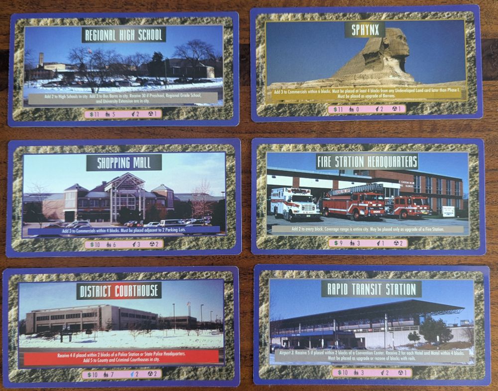 Six extra large Sim City CCG cards, including locatinos like "Regional High School", "District Courthouse", and "Sphynx" (which is literally the sphynx in Egypt).