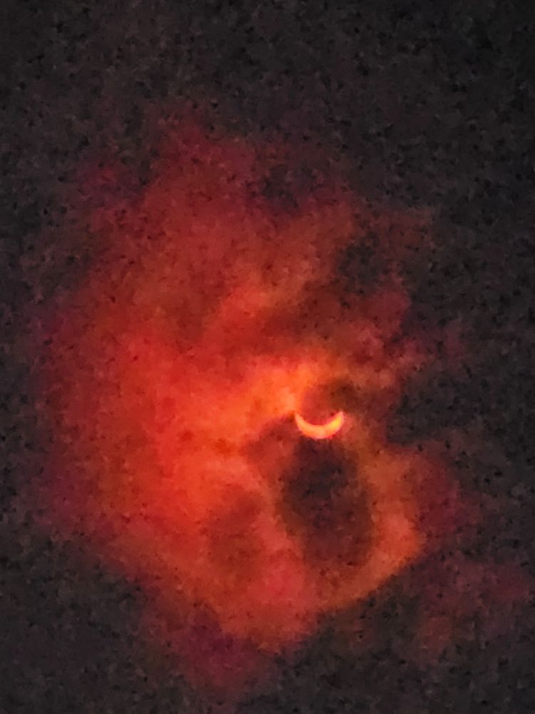 Eclipse 2024 from KY, 97% or so totality. Taken with Samsung Galaxy 22 through eclipse glasses. The moon is covering the top so the sun looks like an orange smile with clouds surrounding it.
