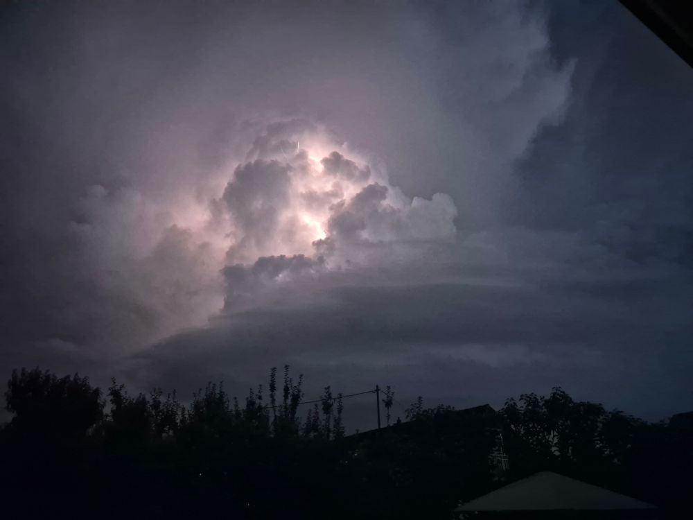 Ein Nacthimmel mit Gewitterwolken. Darin ein Blitz.