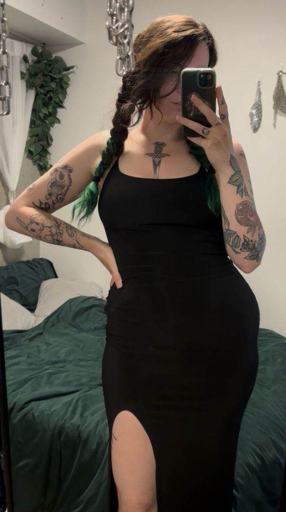 tq in a tight black dress, no sleeves, leg slit at mid thigh.