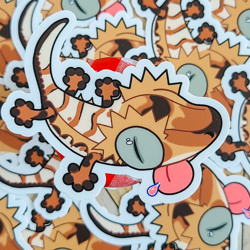 A pile of crested gecko stickers spread out the entirety of the photo. It is various shades of brown with a bright pink tongue sticking out.