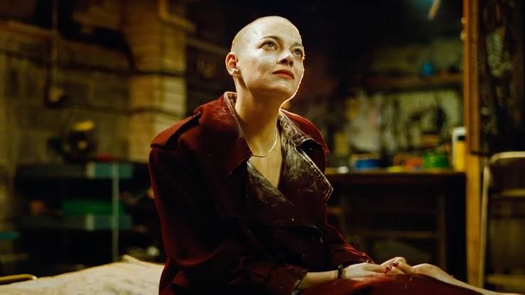 Emma Stone's character Michelle Fuller - bald and covered in white antihistamine cream - looks at a character off-screen.