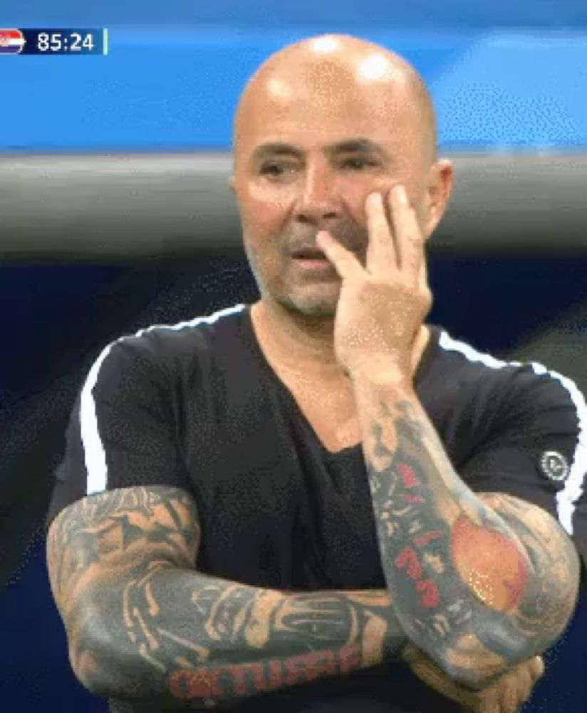 a bald man with tattoos on his arms is looking at something