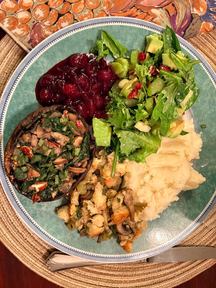A stuffed portobello mushroom, stuffing, mashed potatoes, salad, and cranberry sauce