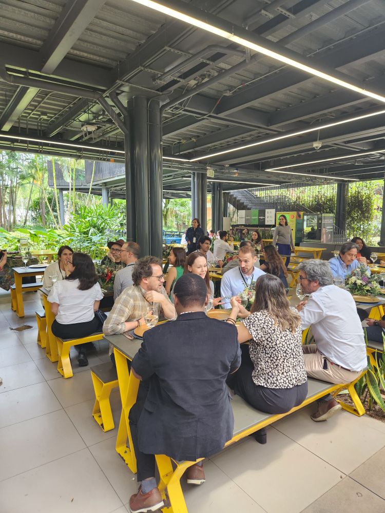 A group of people sit at yellow tables in discussion.