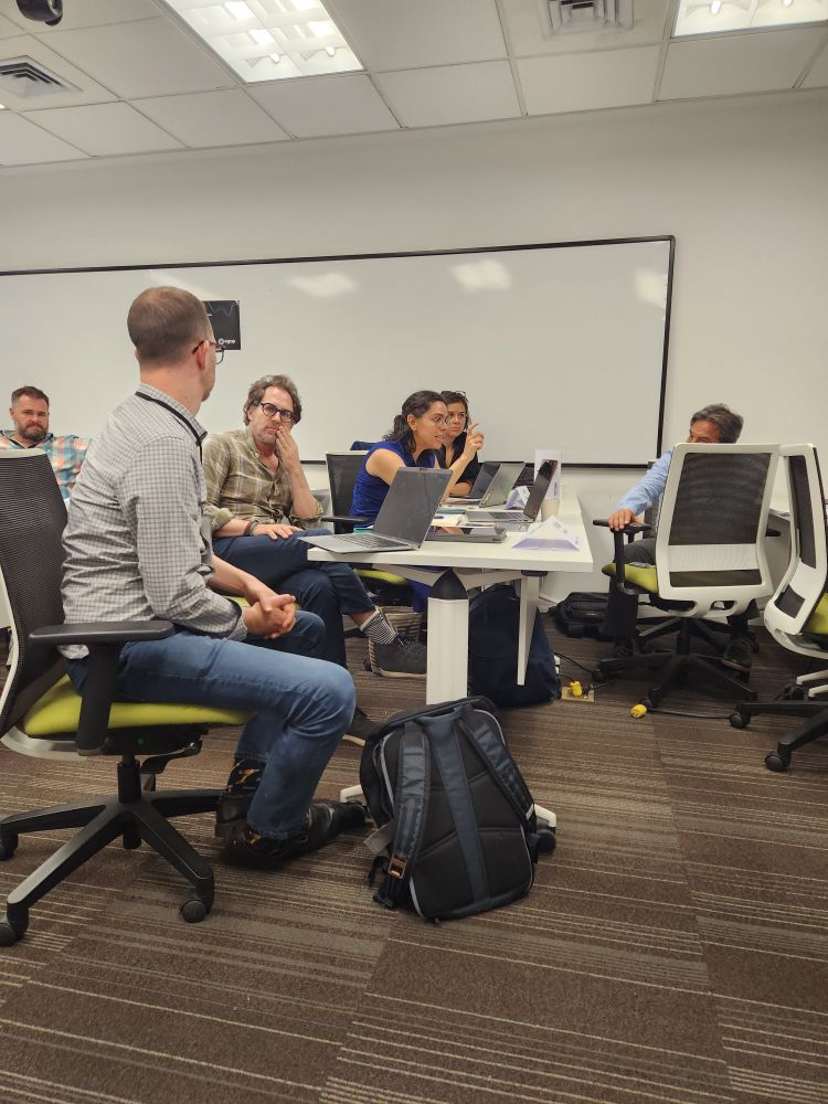 A group of people sitting with laptops in discussion.