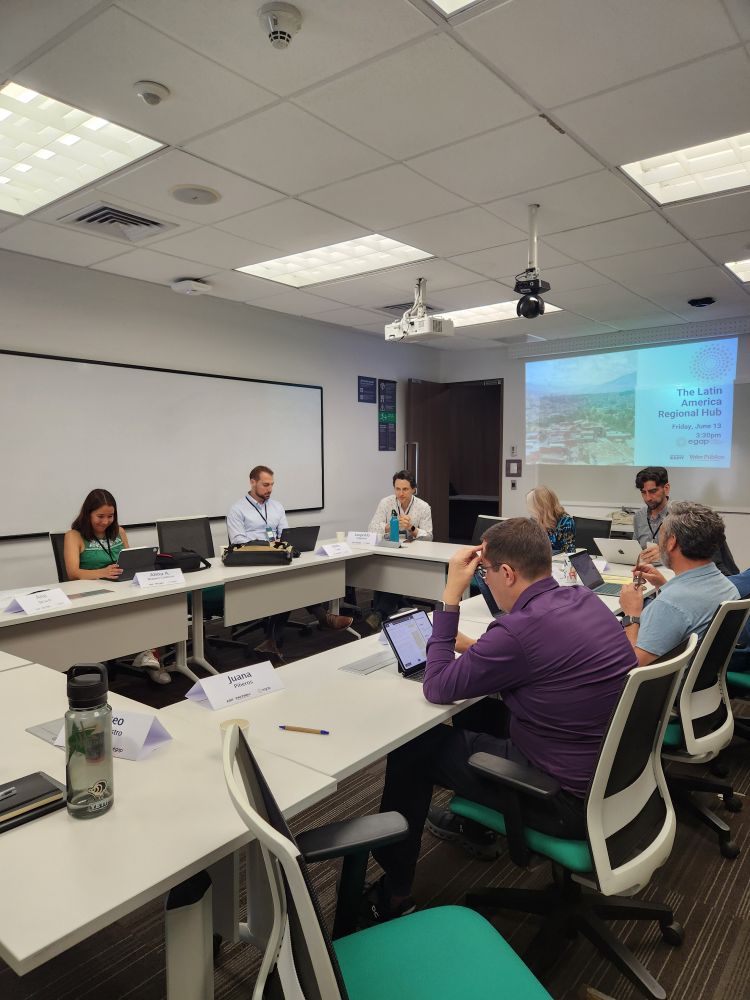 A group of people sitting with laptops in discussion.