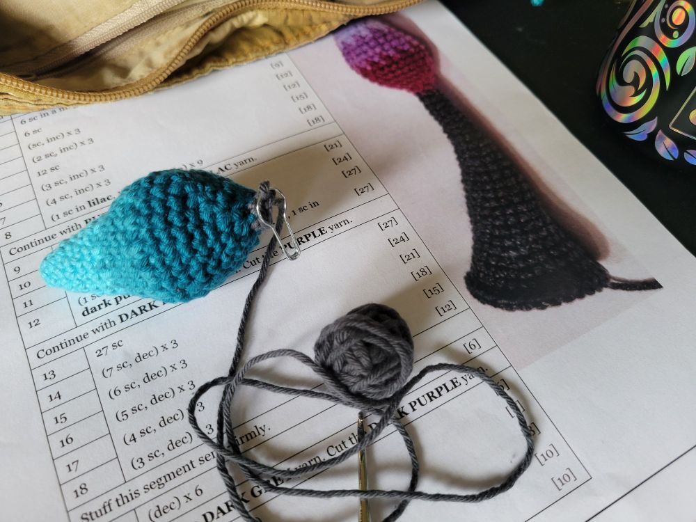 An unfinished crocheted dragon tail, with too little remaining yarn to finish