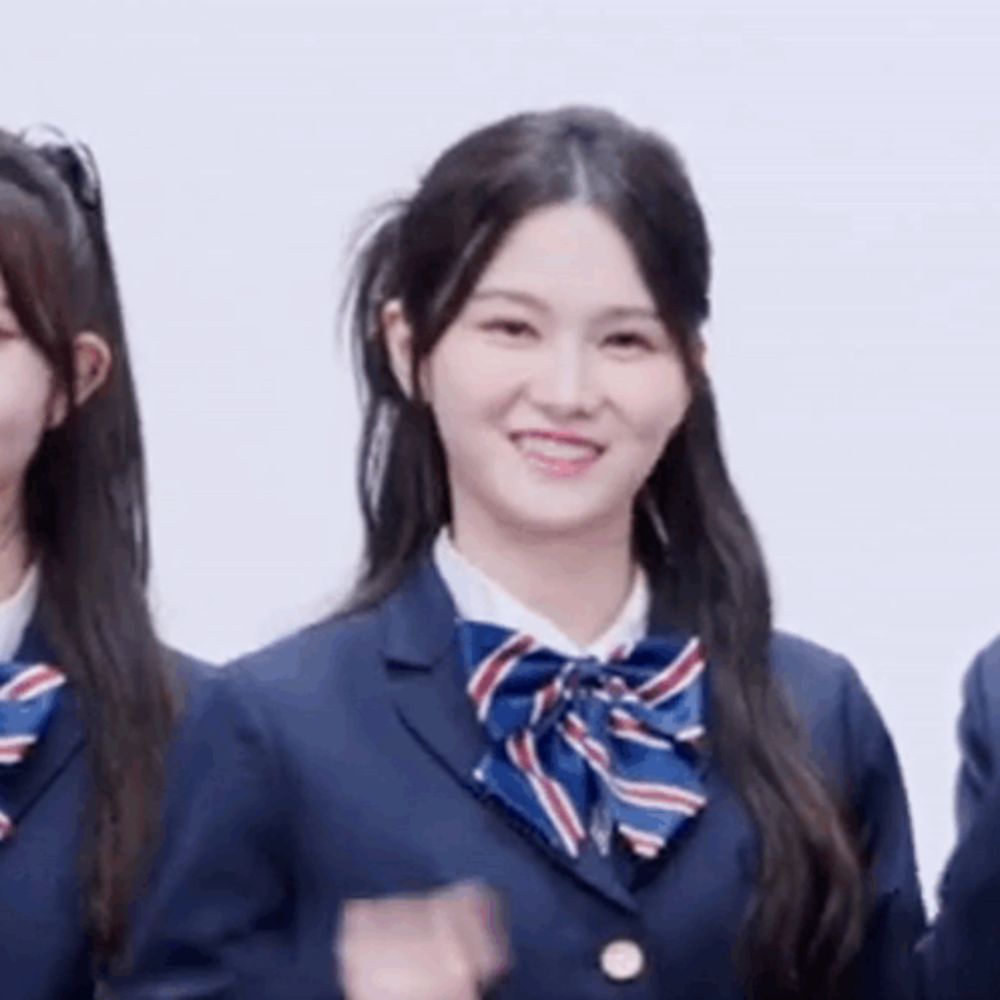 a girl in a school uniform with a bow tie is smiling while standing next to two other girls .