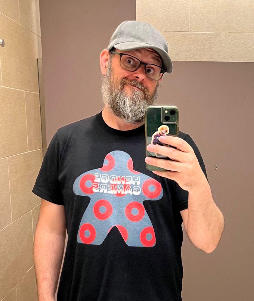 A dude taking a bathroom selfie with an awesome Hendge Gamers shirt on 