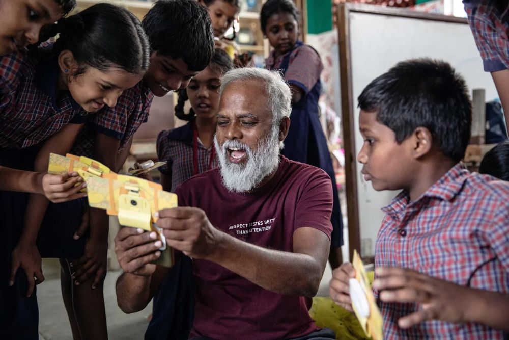 Mo Pandiarajan, founder of Eden school, shows students a view of a specimen in a Foldscope, which he's attached to his mobile phone.
Photo credit: Viraj Nayer for NPR