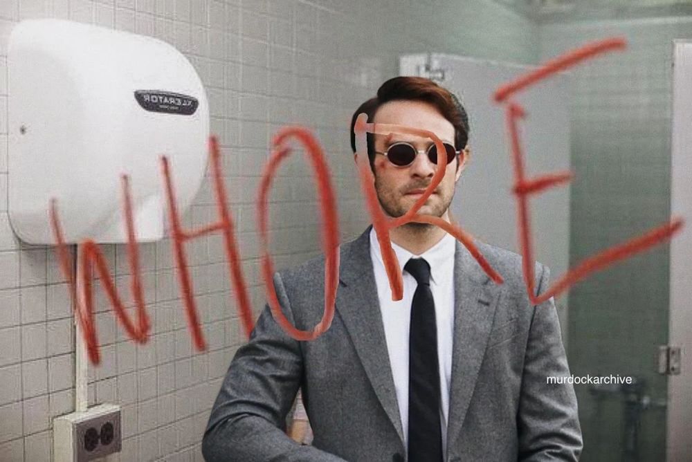 Matt Murdock in a public restroom, with the word "whore" written on the mirror overlayed on top. 