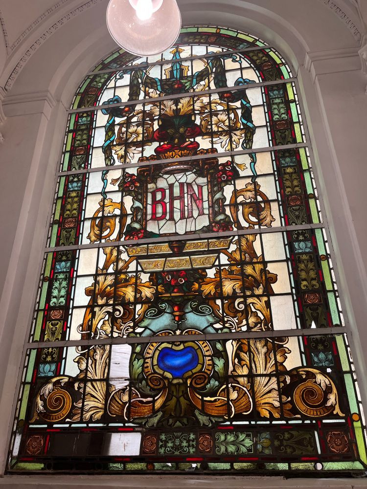 Vitral antiguo colorido con las siglas BHN (Banco Hipotecario Nacional) en el centro.edificio de la Facultad de Filosofía y Ñeyras UBA
