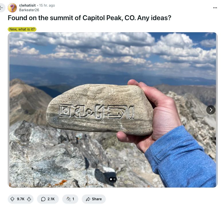 Person holding rock with text on it. Caption reads: Found on the summit of Capitol Peak, CO. Any ideas?