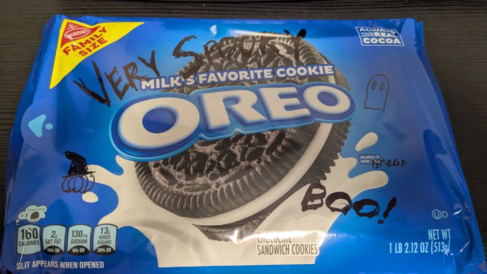 A package of Oreos with "Very Spooky" written across the top in black marker. There's also a "BOO!," a doodle of a ghost, and a pumpkin in a witch's hat