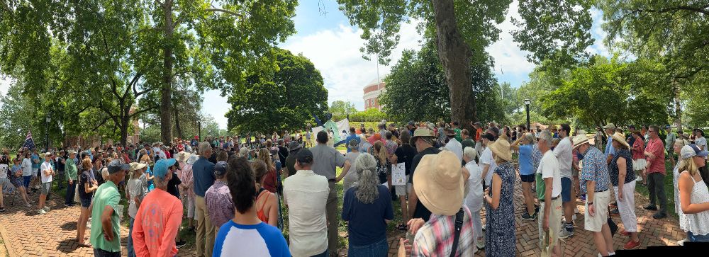 Wide shot from the back of a crowd of hundreds facing the rotunda and listening to the speaker, on the University-Avenue side of the rotunda.