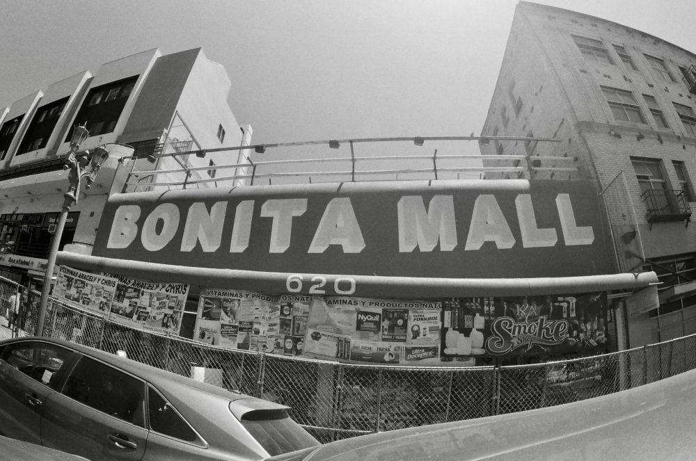 one story building that says “bonita mall”
in huge letters. sidewalk has chainlink fencing to deter street vendors.