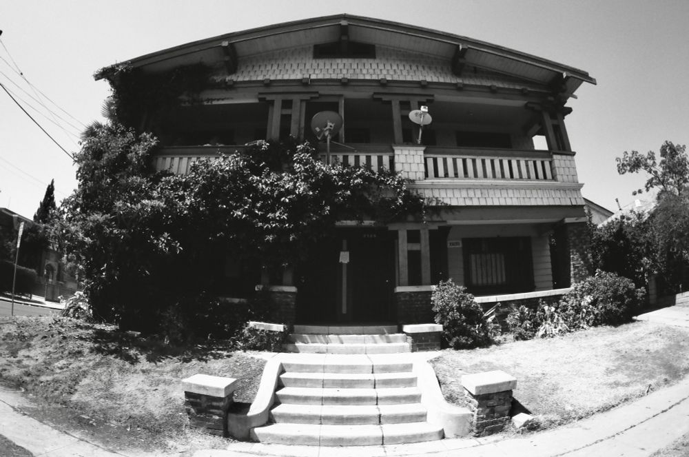 multifamily home with ivy growing on it. satellite dishes on second floor porch/deck