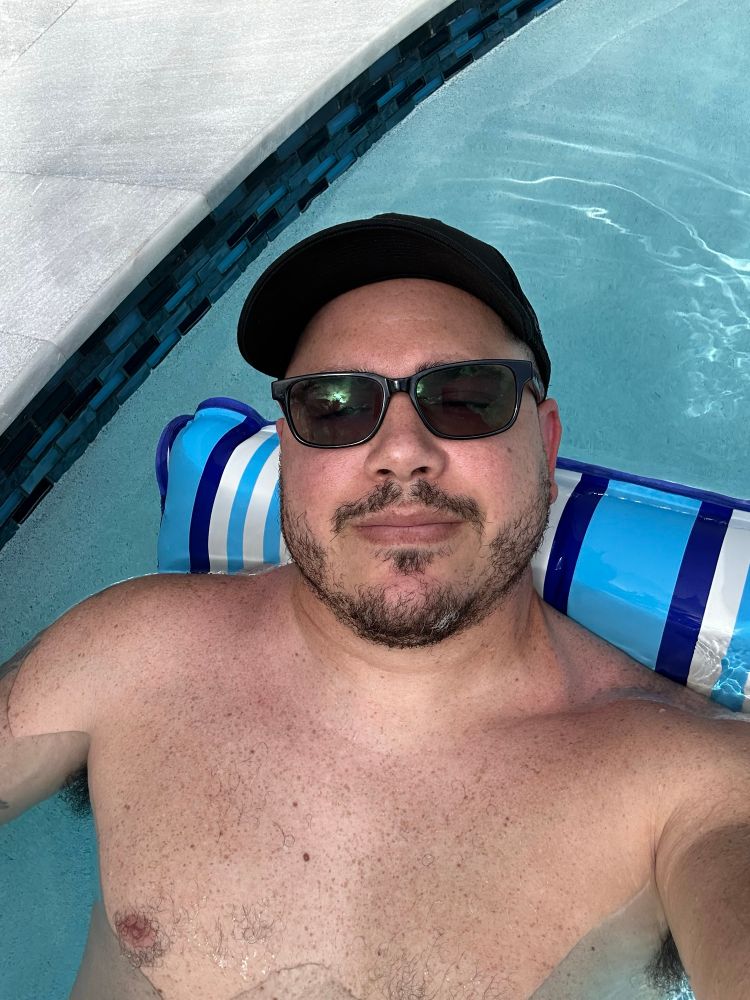 Me floating in the pool with sunglasses and a hat on