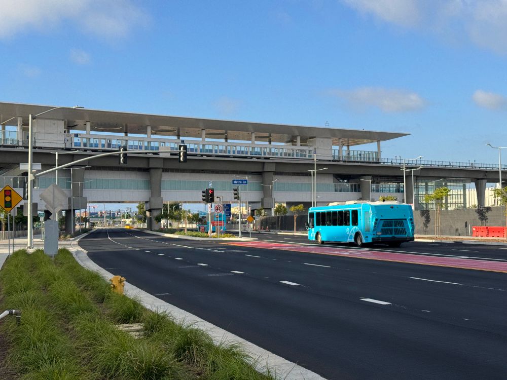 Looking north at Aviation Boulevard towards the automated people mover. An LAX shuttle bus drives north.