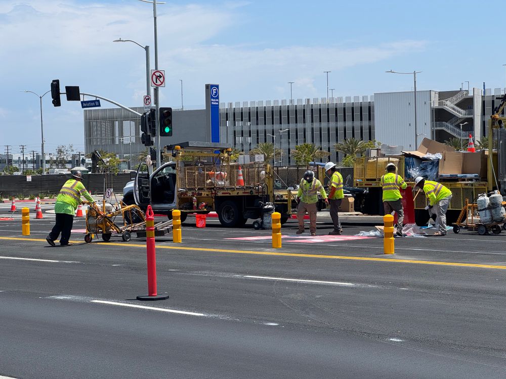 Several road workers add Bus Lane paint to a turning lane. 