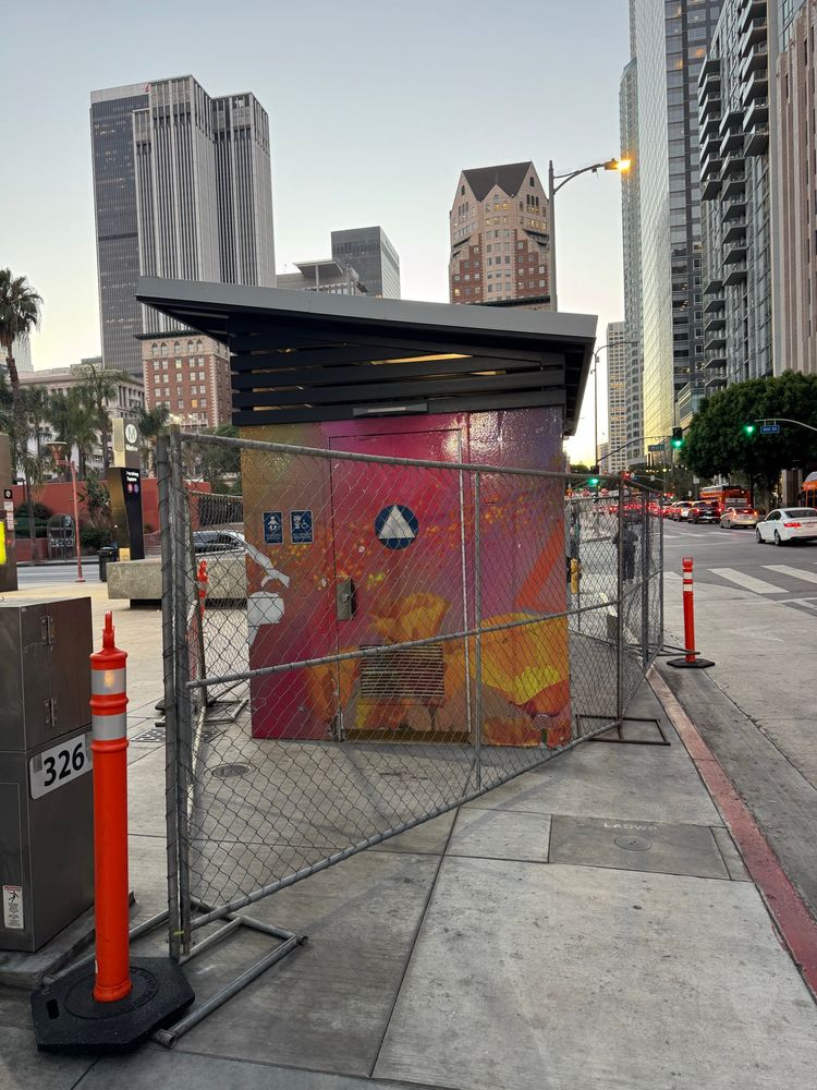 A public city restroom on 5th Street with a fence around it.
