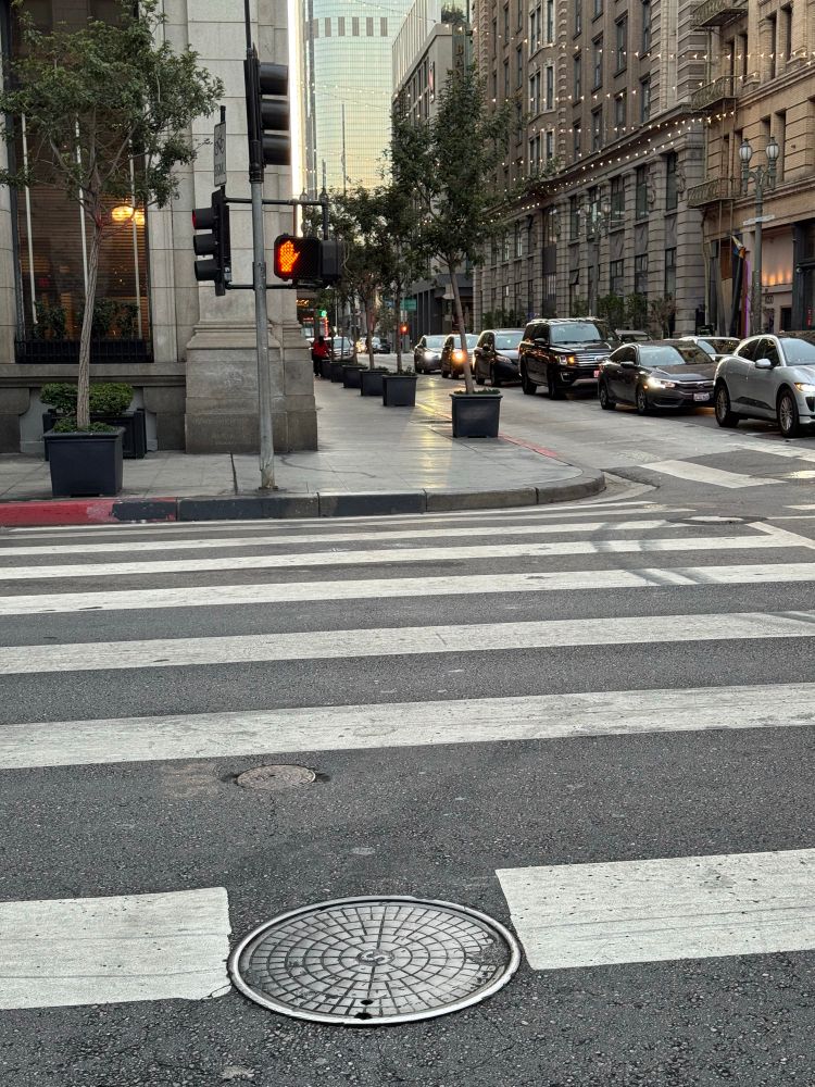 A sidewalk corner curb on fourth and Main with no ADA ramp.