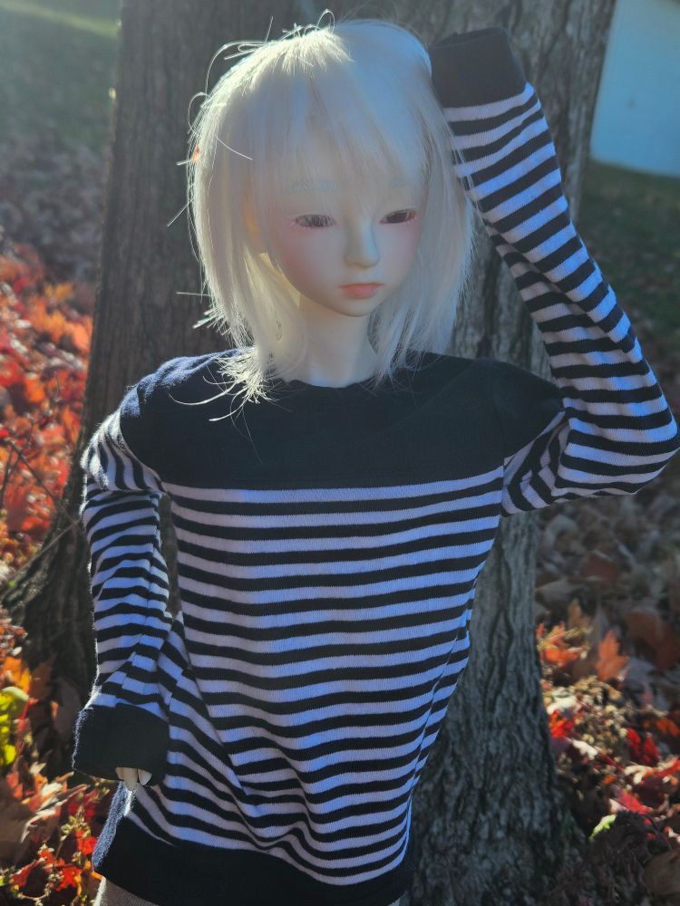 A photo of a BJD with albinism shielding her eyes from the sun
