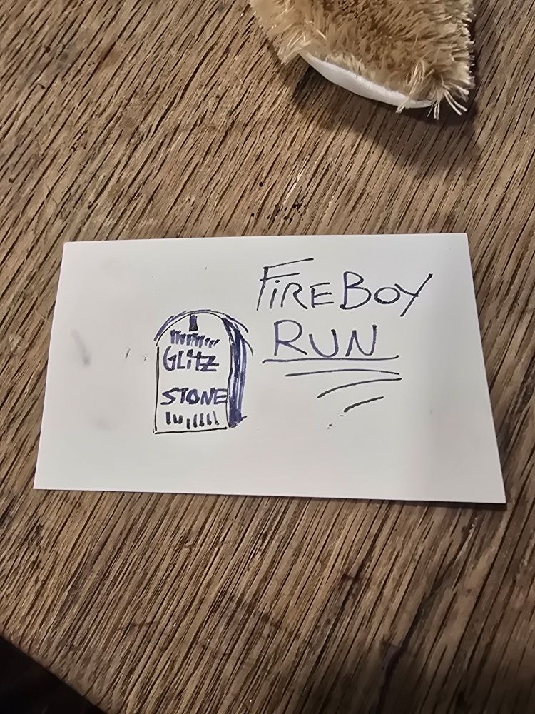 A drawing of a tombstone-like thing with "GLITZ STONE" written on it. In the same ink, next to the thing, thrice underlined text reads "FIREBOY RUN".