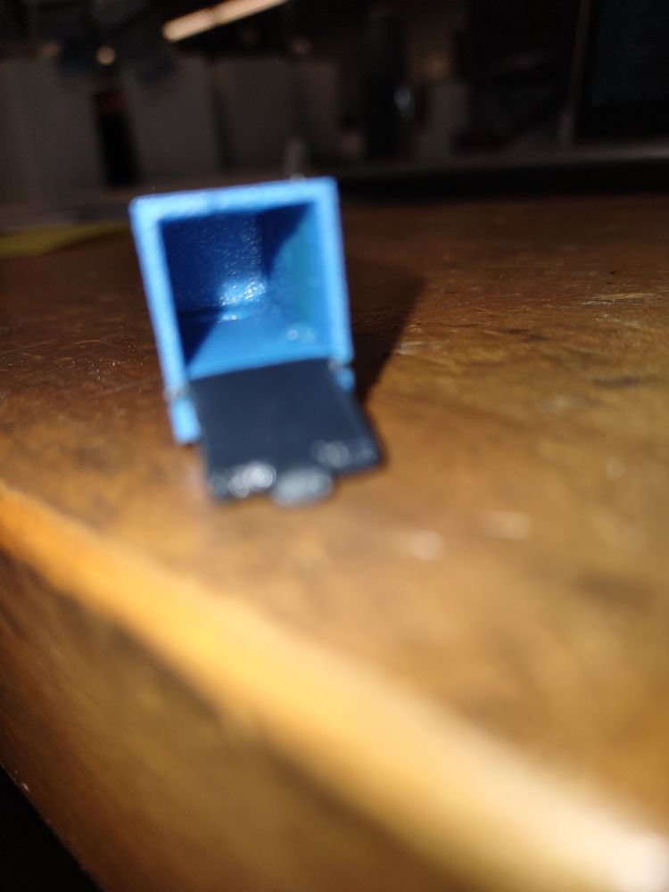 A blurry picture showing the inside of an empty 3D printed blue toy trailer.