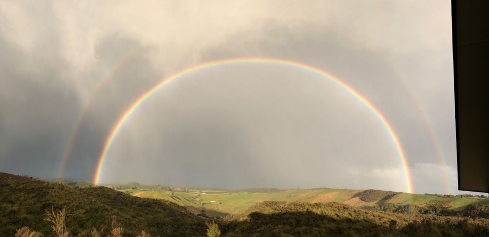 Wide-angle pic of a double rainbow spanning hillside to hillside