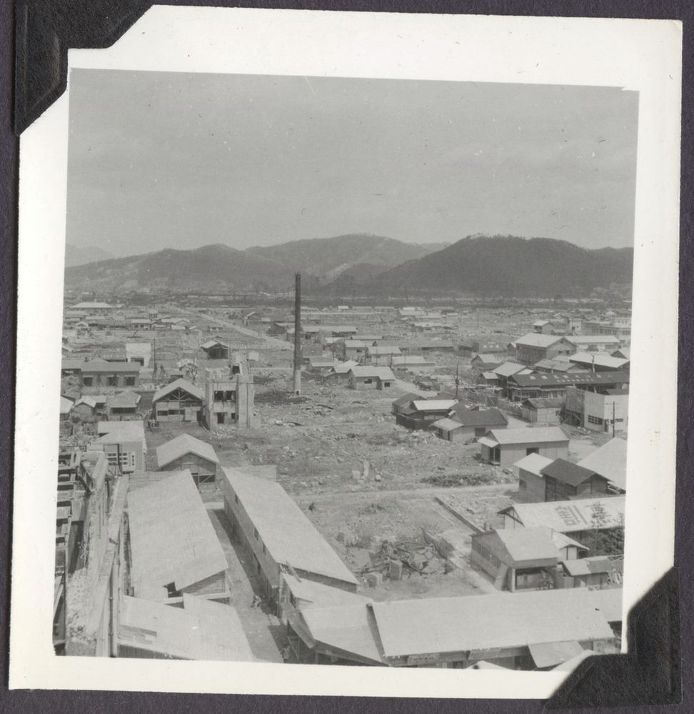 A free-standing smokestack amidst rubble and damaged buildings in Hiroshima, two years after the bombing.