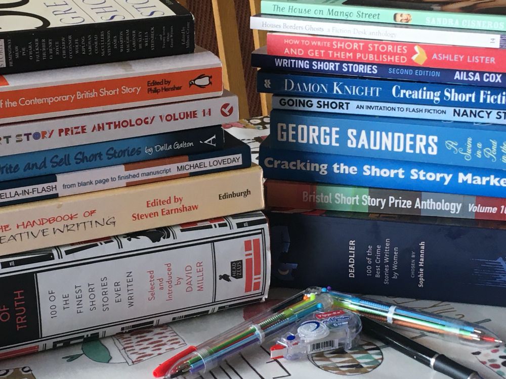 Two piles of books, including anthologies of short stories, and books about writing short stories.