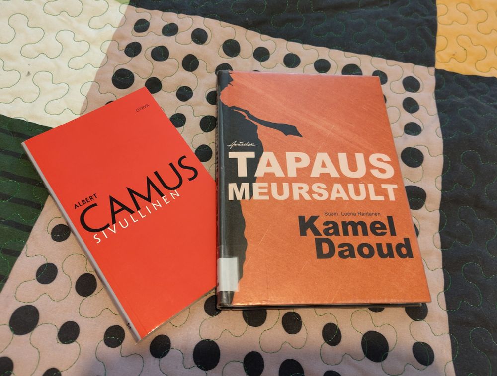 Albert Camus'n Sivullinen ja Kamel Daoudin Tapaus Meursault -kirjat päiväpeitolla.