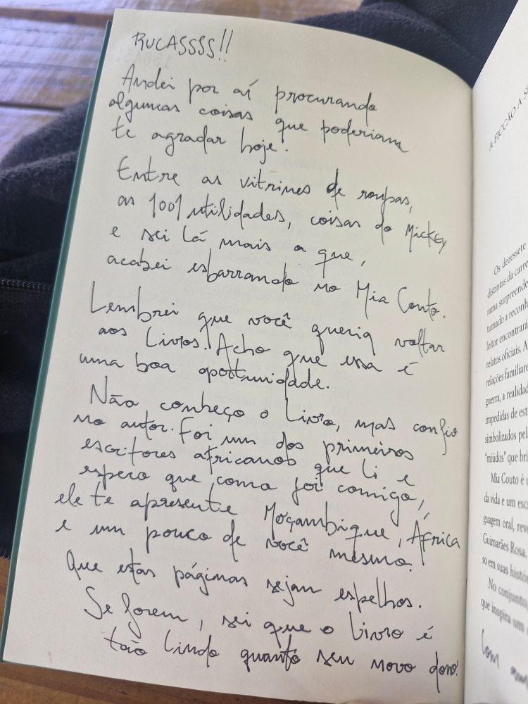 Dedicatória na primeira página do livro escrita a caneta:
"RUCASSSS!!
Anderi por aí procurando algumas coisas que poderiam te agradar hoje. Entre as vitrine de roupas, as 1001 utilidades, coisas do Mickey e sei lá mais o que acabei esbarrando no Mia Couto.
Lembrei que você queria voltar aos livros. Acho que essa é uma boa oportunidade. Não conheço o livro, mas confio no autor. Foi um dos primeiros escritores africanos que li e espero que, como foi comigo, ele te apresente Moçambique, África e um pouco de você mesmo. 
Que estas páginas sejam espelhos.
Se forem, sei que o livro tão lindo quanto seu novo dono."