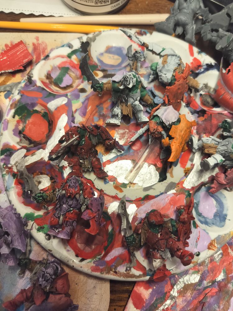 A pile of three orruks wearing heavily shaded red and purple armour 