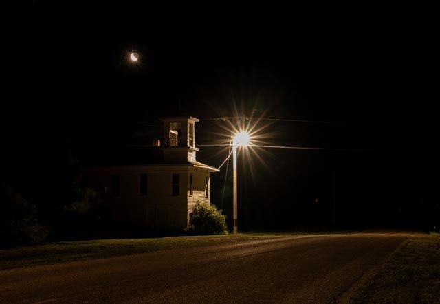 Night image of an abandoned building with cresent moon overhead.