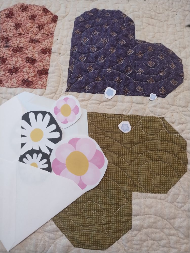 An envelope with flower stickers coming out of it. It has pink flowers, small forget me not flowers, and daisy flowers, all as stickers 