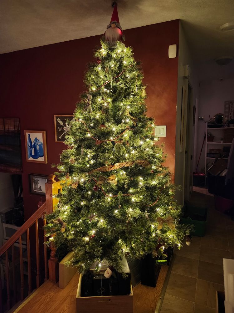 A fluffy large fake yule tree lit with soft yellow lights.