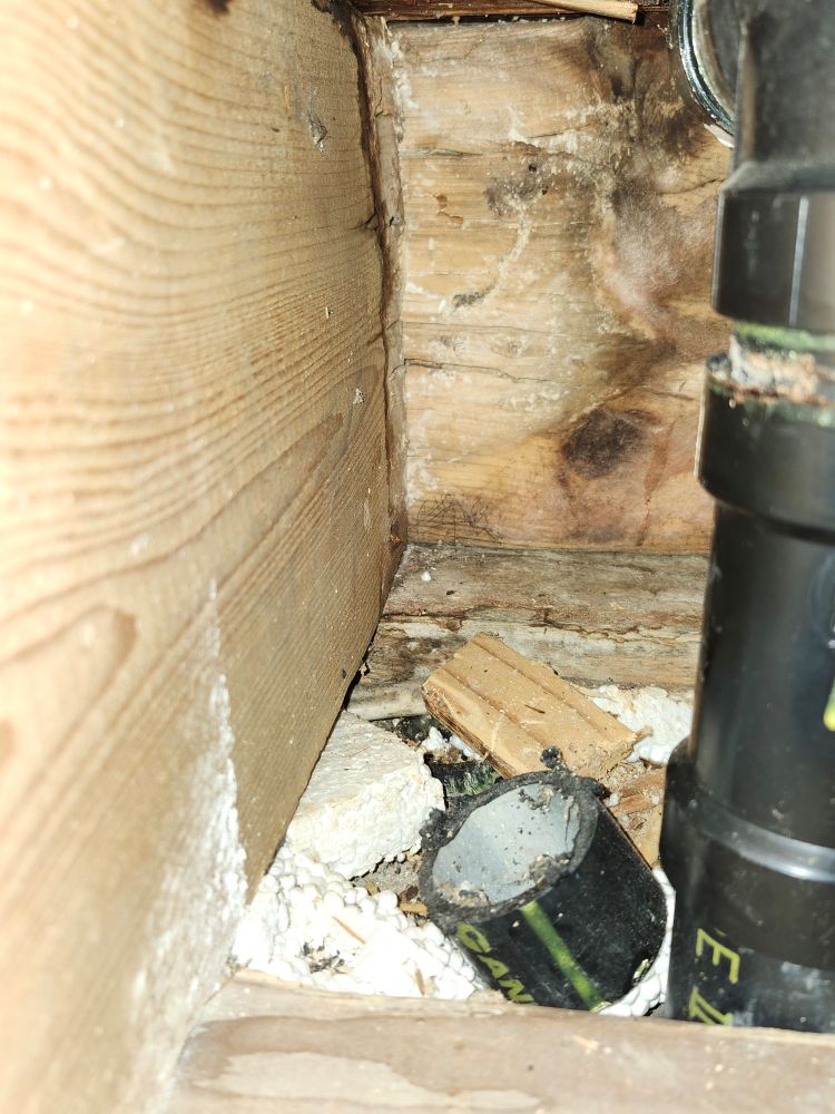 Photo showing old water damage and rot on wood around plumbing in joists and supporting structure of house.