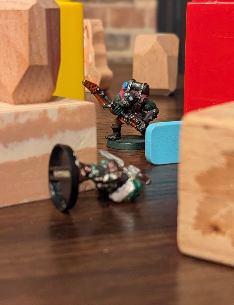 An ork miniature standing over a knocked over space soldier miniature