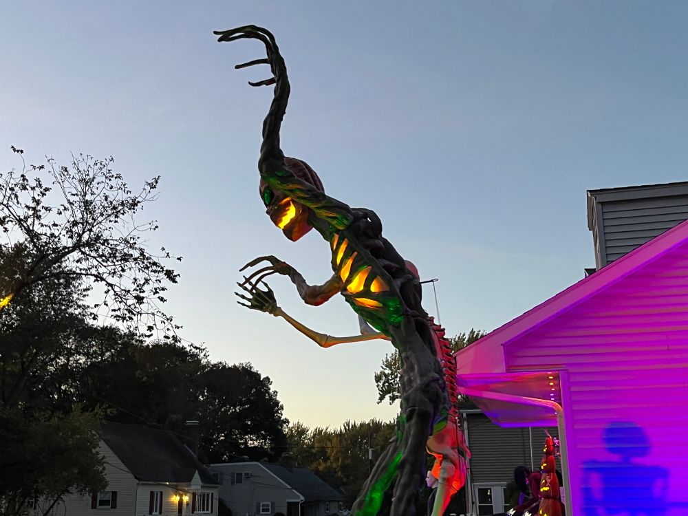 A side shot of two giant skeletons in front of someone’s house. In love with the contrast of the setting sun and the purple lighting against the house.