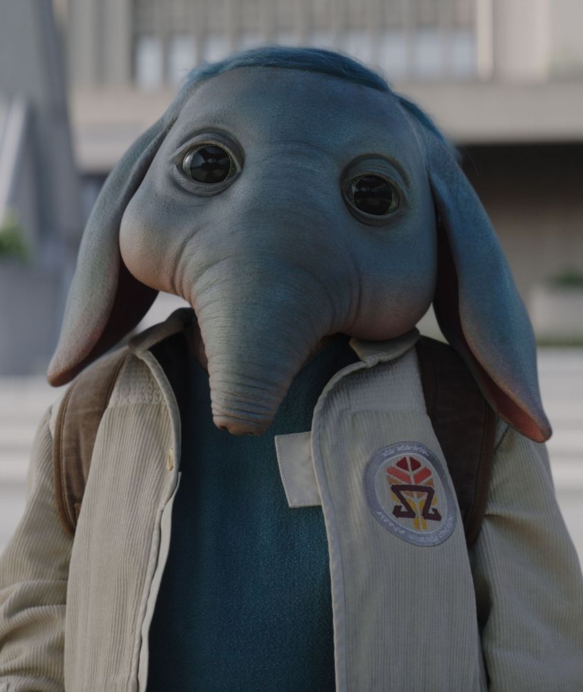 Neel, a kid alien from Star Wars: Skeleton Crew. Neel has big, expressive eyes, a tapir-like nose, big floppy ears, and blue skin