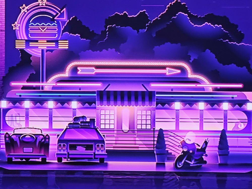 Picture of the Roku City screensaver. The retro style diner with neon burger sign has a Jurassic Park reference in the right window. The same view of a velociraptor peeking through the window like in the kitchen scene of Jurassic Park.