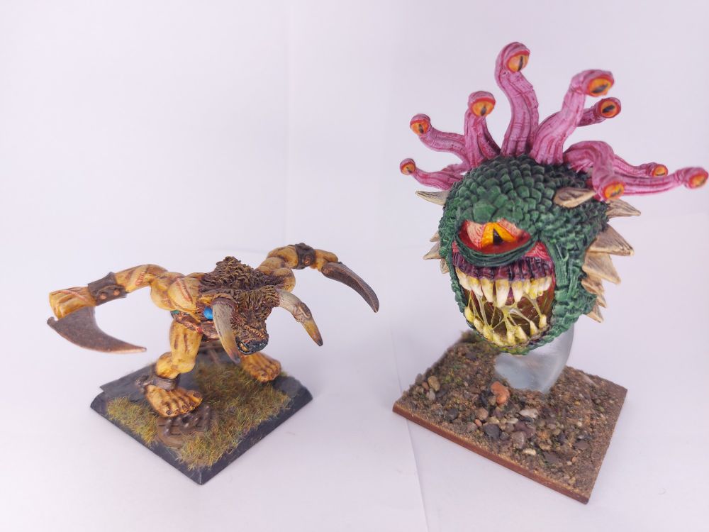 A Minotaur and Beholder.
The Minotaur, a large humanoid with the head of a bull, is bent over charing head first with its arms out to each side holding curved bonze swords.
The Beholder is a floating Sphere with one giant bloodshot eye and a massive mouth that take up most of the front. It has a lot of long sharp teeth. The Sphere is green and scaled 10 tentacles sprout from the Sphere each with an eye at the end.