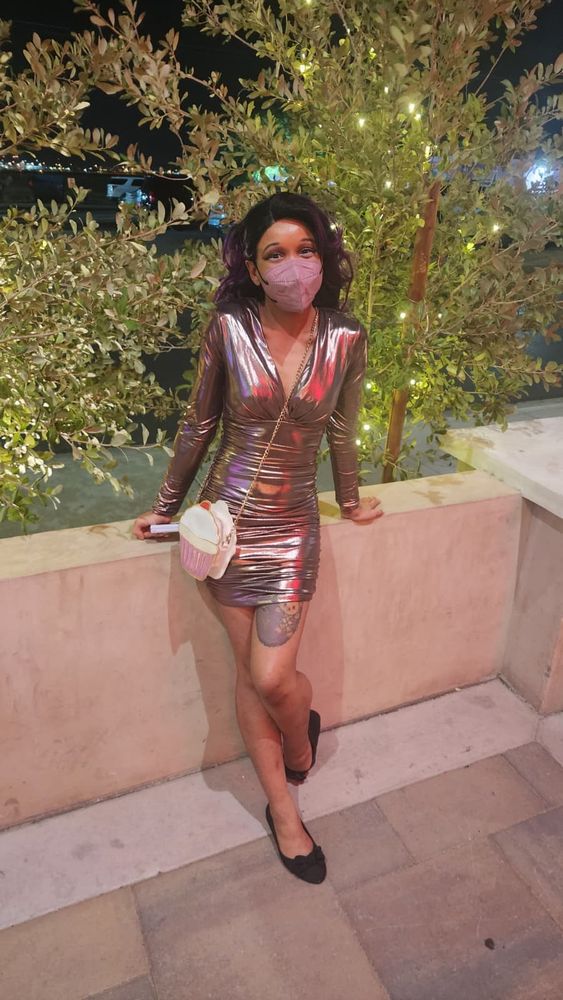 Cupcake in a metallic rose gold dress, a cupcake purse, and a mauve n95 posing for a picture
