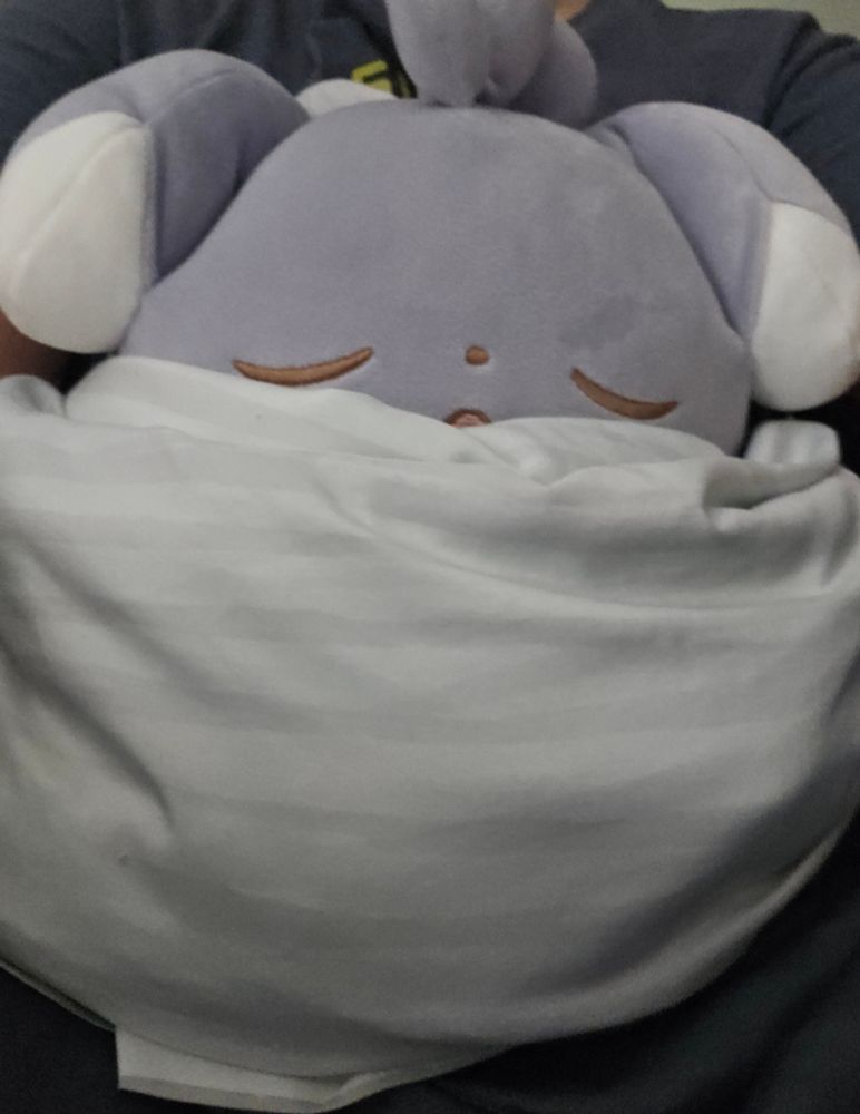 A very soft sleepy Espurr plusbie all tucked into the covers and ready for bed!! If unfamiliar w the pokemon espurr imagine the Autism Creature but very fluffy and grey with droopy ears and he stands on two legs.