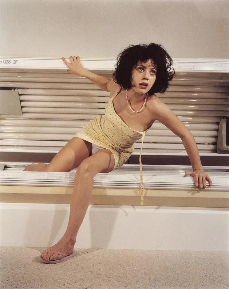 Foto a Fairuza Balk con un vestito corpo giallo e infradito che esce da un solarium, o almeno mi sembra.