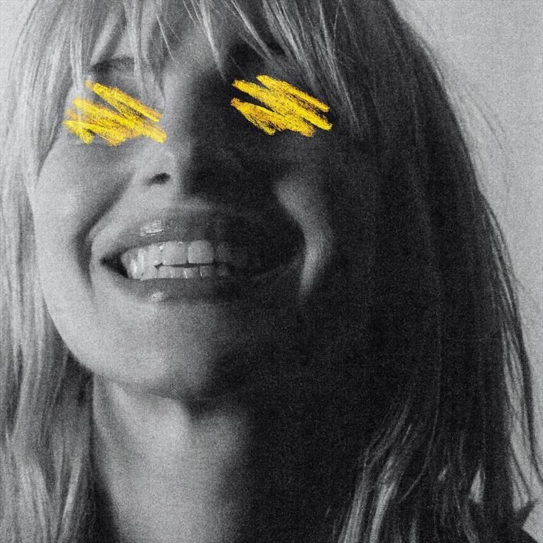 Primo piano ad Hayley Williams sorridente. Disegnati di giallo sulla foto, sopra gli occhi, ci sono due scarabocchi.